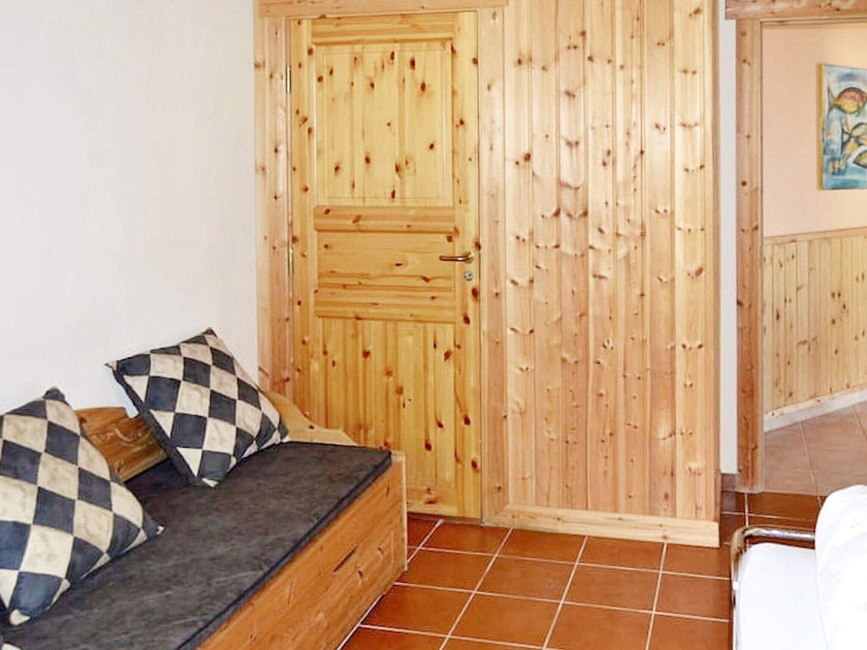 A room with a wooden door, a checkered sofa, and a tiled floor.