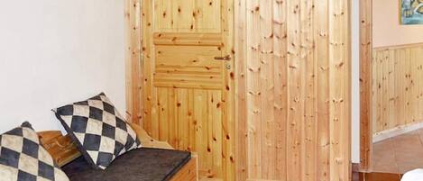 A room with a wooden door, a checkered sofa, and a tiled floor.