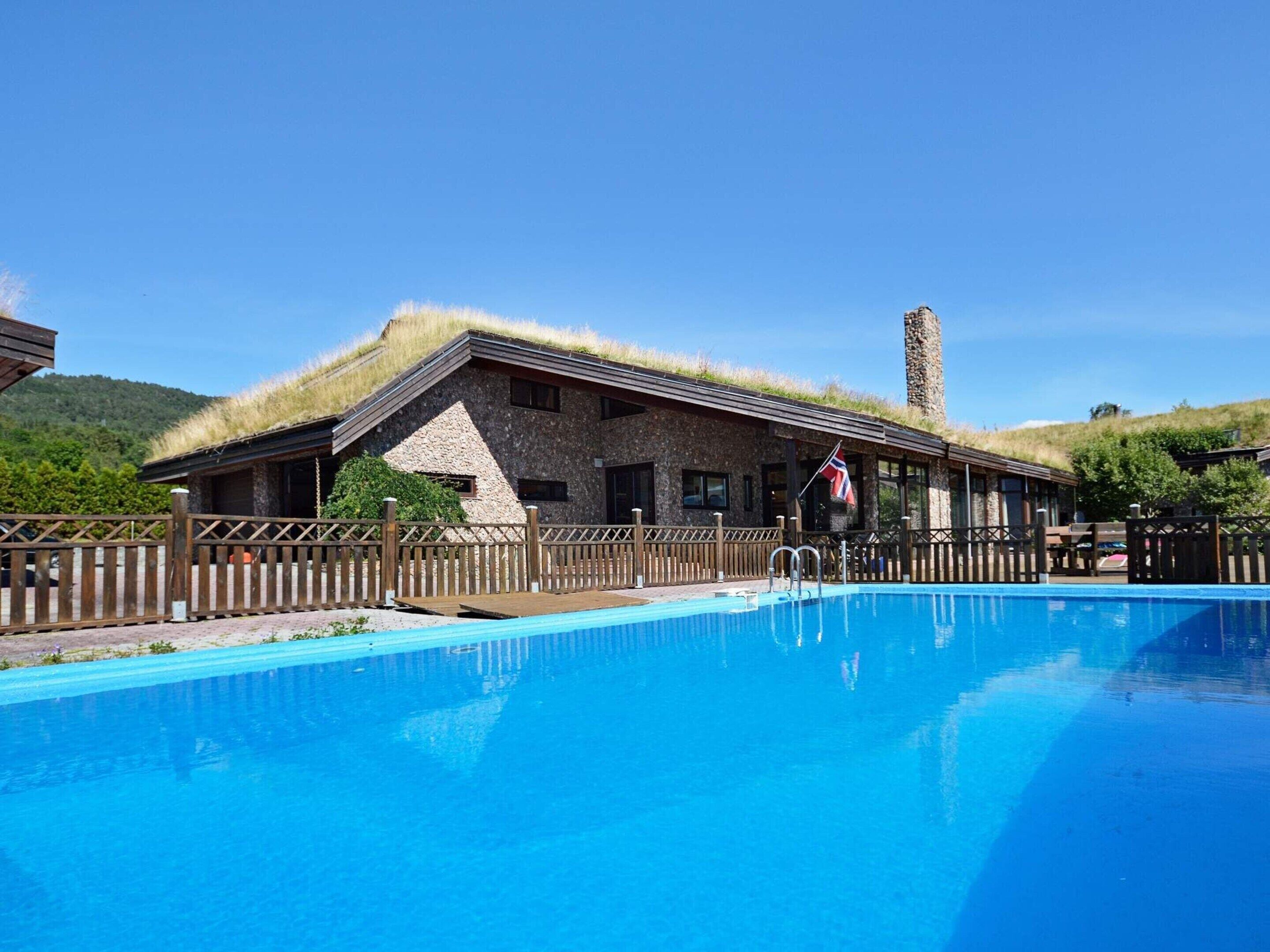 A building with a thatched roof, a swimming pool, and a flag.