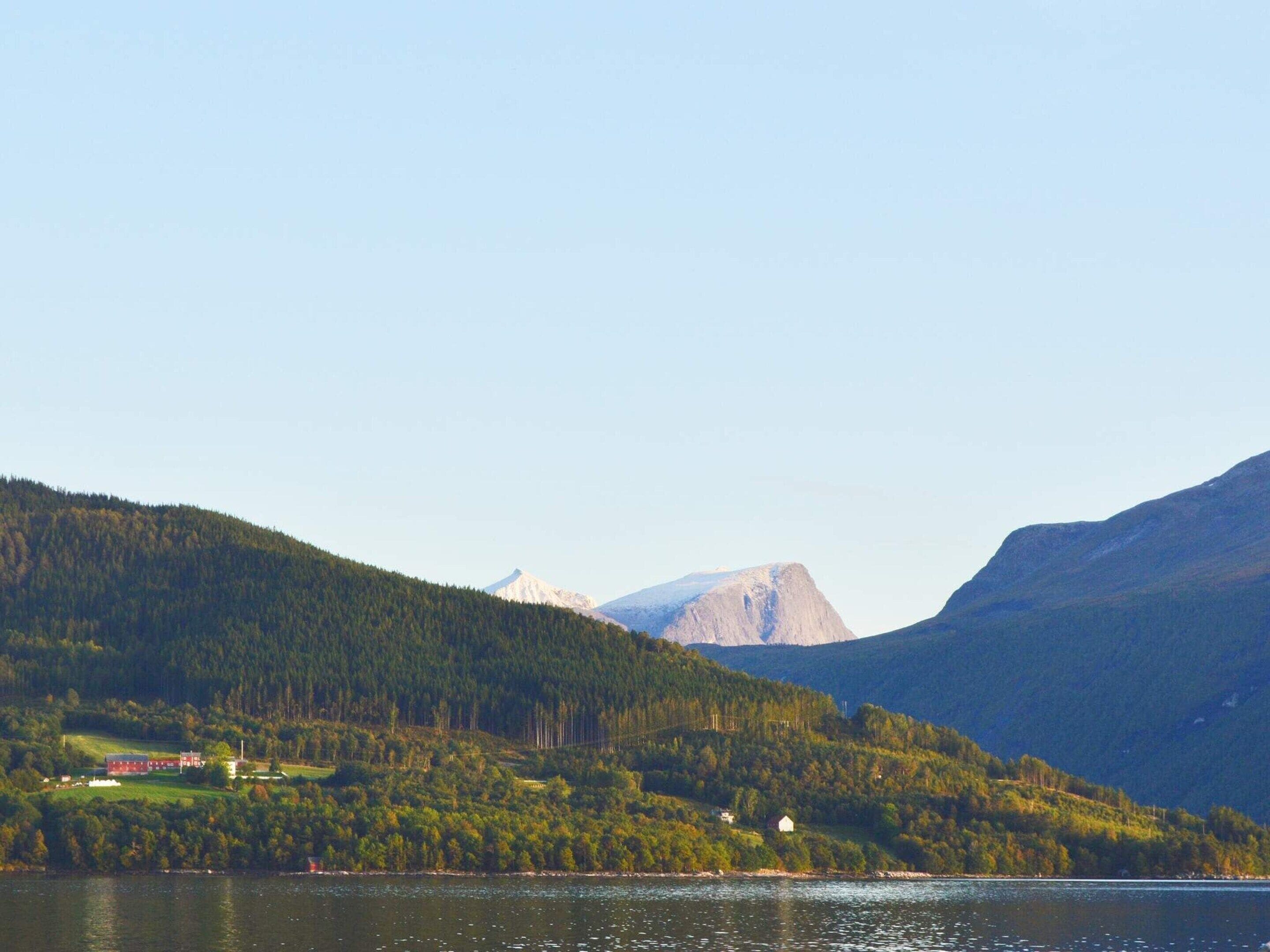 Un lac entouré de collines boisées, avec une montagne en arrière-plan.