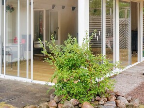 A modern house with a glass door entrance, a small garden with rocks, and a wooden deck.