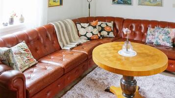 A brown leather sofa with a round wooden coffee table in a room with a white carpet.