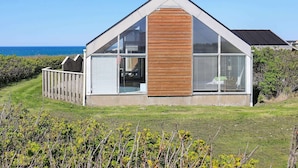 A modern house with a large glass window, a wooden facade, and a view of the sea. - 6 Person Holiday Home in Lokken-by Traum (Lokken)