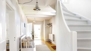A bright hallway with a white staircase, a bench, and a radiator. - Holiday Home in Hova (Hova)