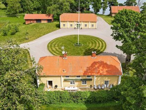 A large house with a red-tiled roof, a circular driveway, and a well-maintained lawn. - Holiday Home in Hova (Hova)