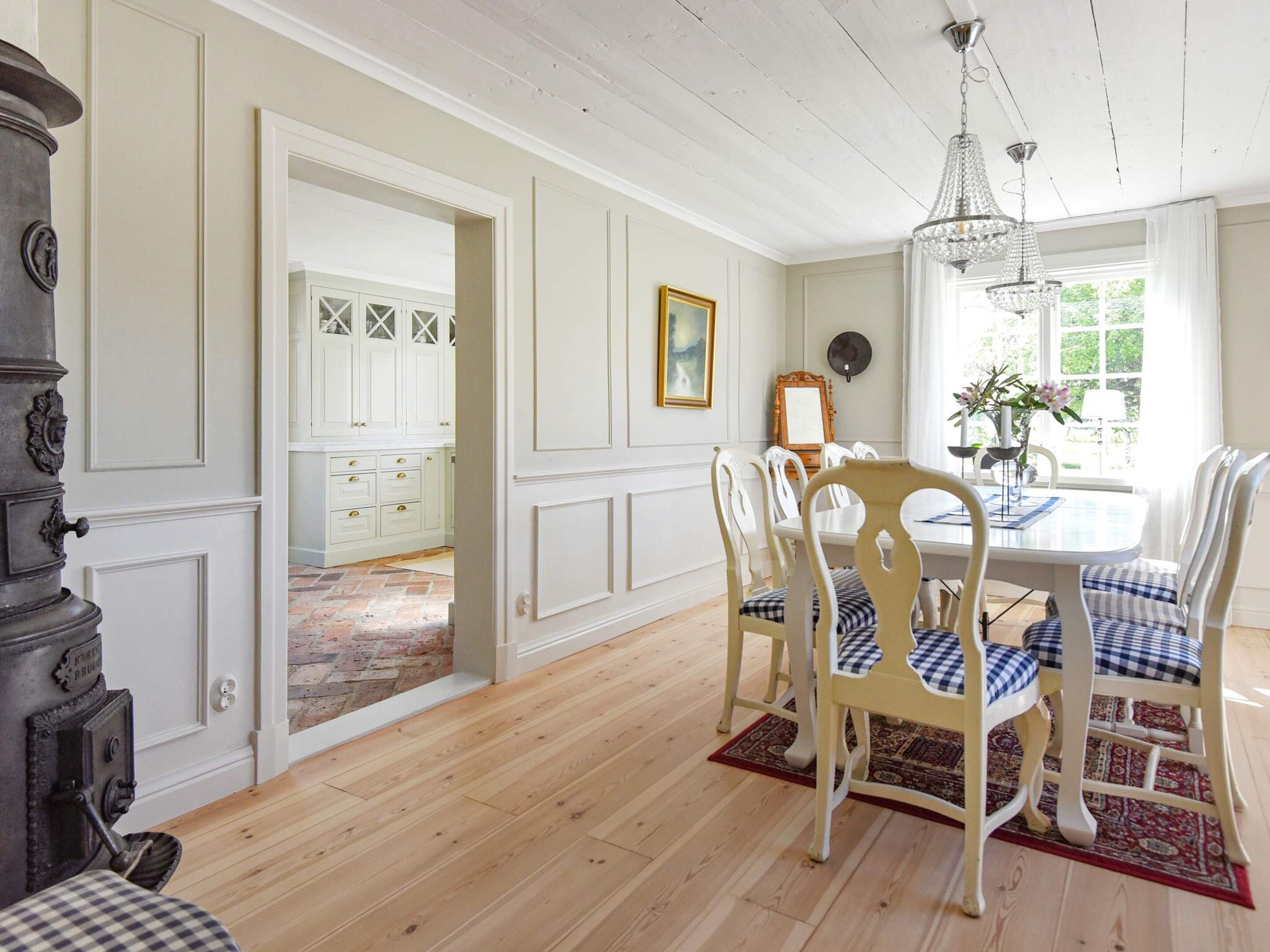 A dining area with a wooden table, white chairs, and a chandelier.