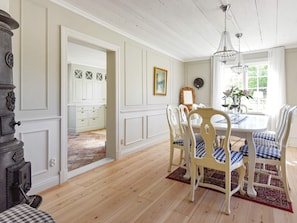 A dining area with a wooden table, white chairs, and a chandelier. - Holiday Home in Hova (Hova)