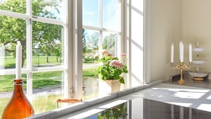 A modern kitchen with a large window, a glass-top table, and a view of a green park. - Holiday Home in Hova (Hova)