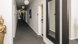 A hallway with a Buddha statue, framed mirrors, and a carpeted floor.