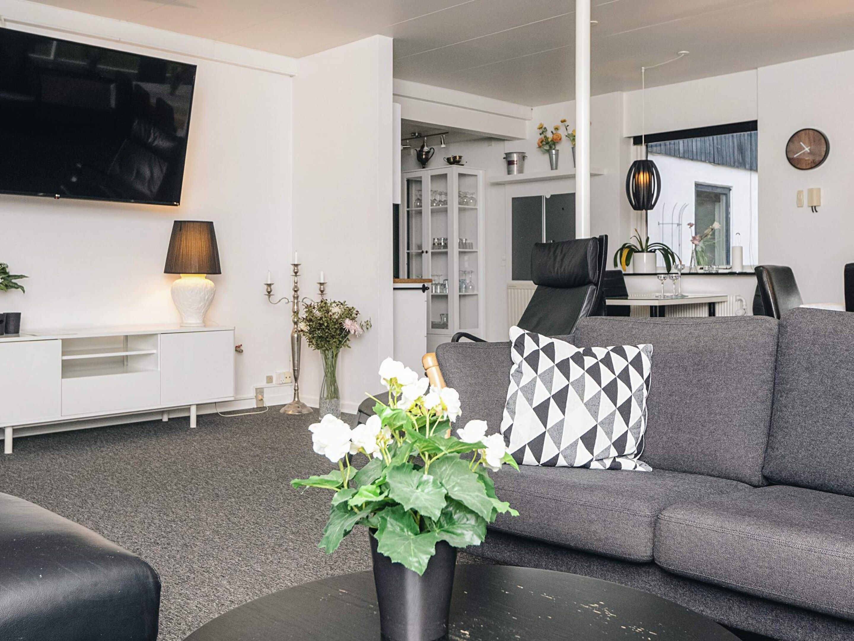 A modern living room with a grey sofa, a black coffee table, and a white entertainment unit.