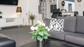 A modern living room with a grey sofa, a black coffee table, and a white TV on the wall.