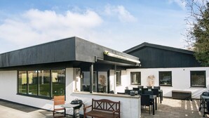 A modern outdoor patio with a grill, seating, and a view of the backyard.