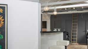 A modern kitchen with a bar area, wooden ceiling beams, and a ladder against the wall. - 4 Star Holiday Home in Oksbol (Oksbol)