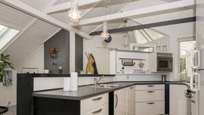 A modern kitchen with a central island, white cabinetry, and a black countertop. - 4 Star Holiday Home in Oksbol (Oksbol)