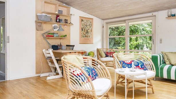 A cozy room with a wooden floor, wicker chairs, a small table, and a green-striped sofa. - 6 Person Holiday Home in Knebel-by Traum (Knebel)