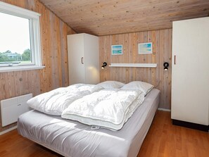 A bedroom with a bed, wooden walls, a window, and a white wardrobe. - 6 Person Holiday Home in Hjorring (Hjørring)