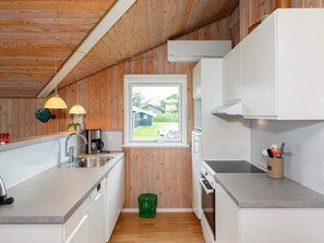 A compact kitchen with wooden walls, a window, and modern appliances. - 6 Person Holiday Home in Hjorring (Hjørring)