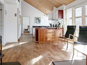 A modern kitchen with wooden cabinets, a central island, and a dining area with chairs.