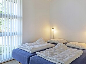 A bedroom with a bed, pillows, and a bedside lamp.