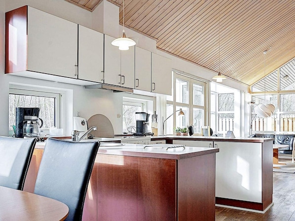 A modern kitchen with a central island, pendant lighting, and large windows.