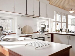 A modern kitchen with white cabinetry, a stainless steel sink, and a built-in stove.