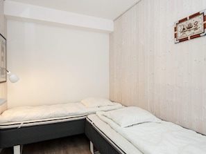 A bedroom with two beds, a bedside lamp, and a framed picture on the wall. - Holiday Home in Wendtorf (Wendtorf)