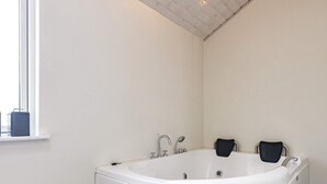 A modern bathroom with a freestanding bathtub, a window, and a tiled floor. - 5 Star Holiday Home in Skals (Skals)