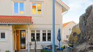 A two-story house with a tiled roof, a front door, and a small patio area with a table and chairs. - Holiday Home in Skärhamn (Skaerhamn)