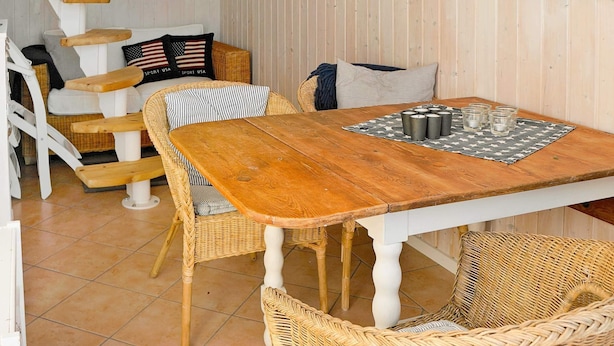 A dining area with a wooden table, wicker chairs, and a map on the wall. - Holiday Home in Skärhamn (Skaerhamn)
