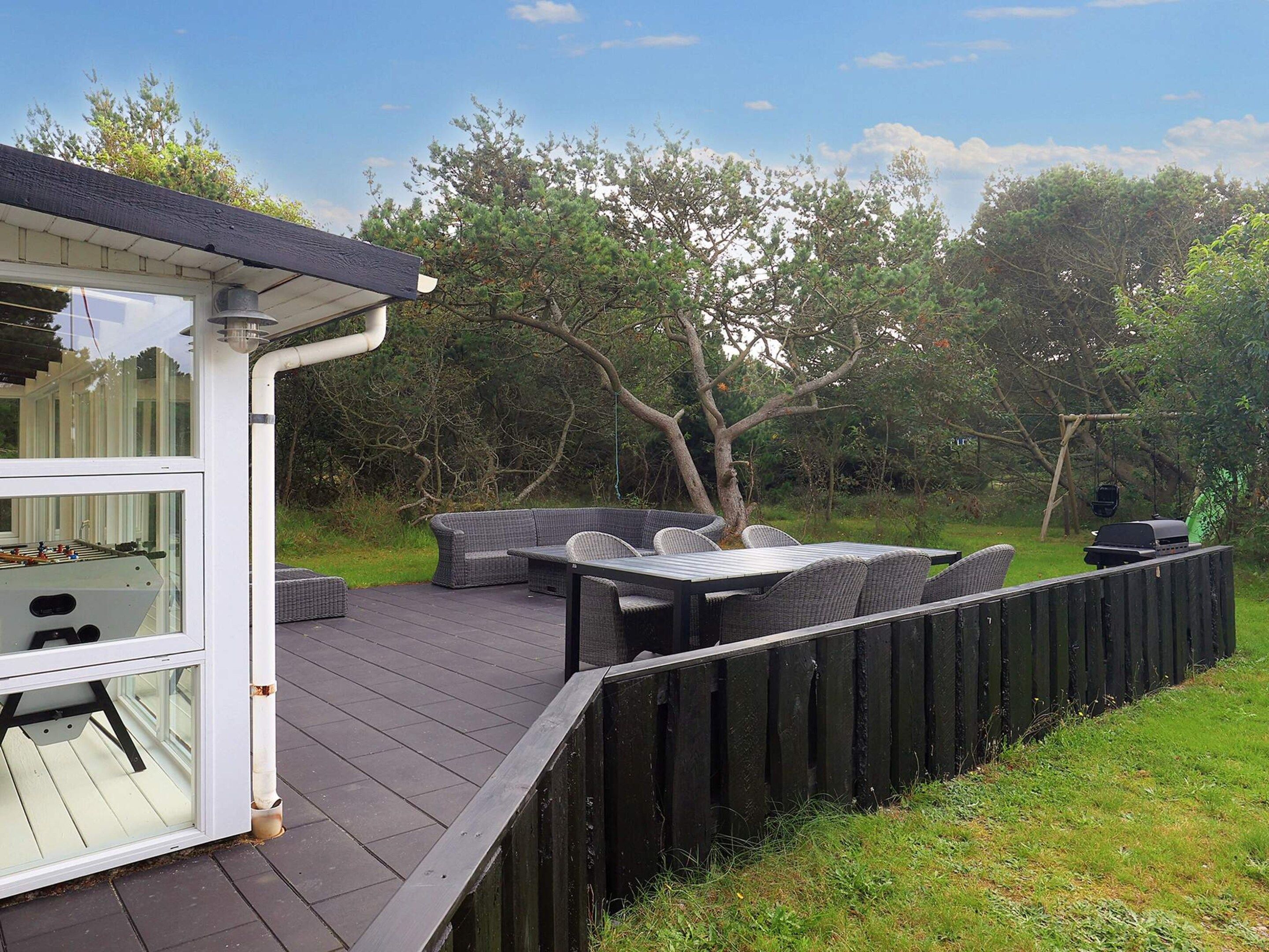 A deck with outdoor furniture, a grill, and a wooden fence.