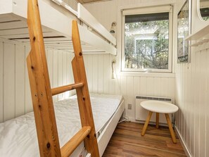 A bunk bed room with a wooden ladder, a small bedside table, and a window with a view of trees. - 4 Star Holiday Home in Vejers Strand (Vejers Strand)