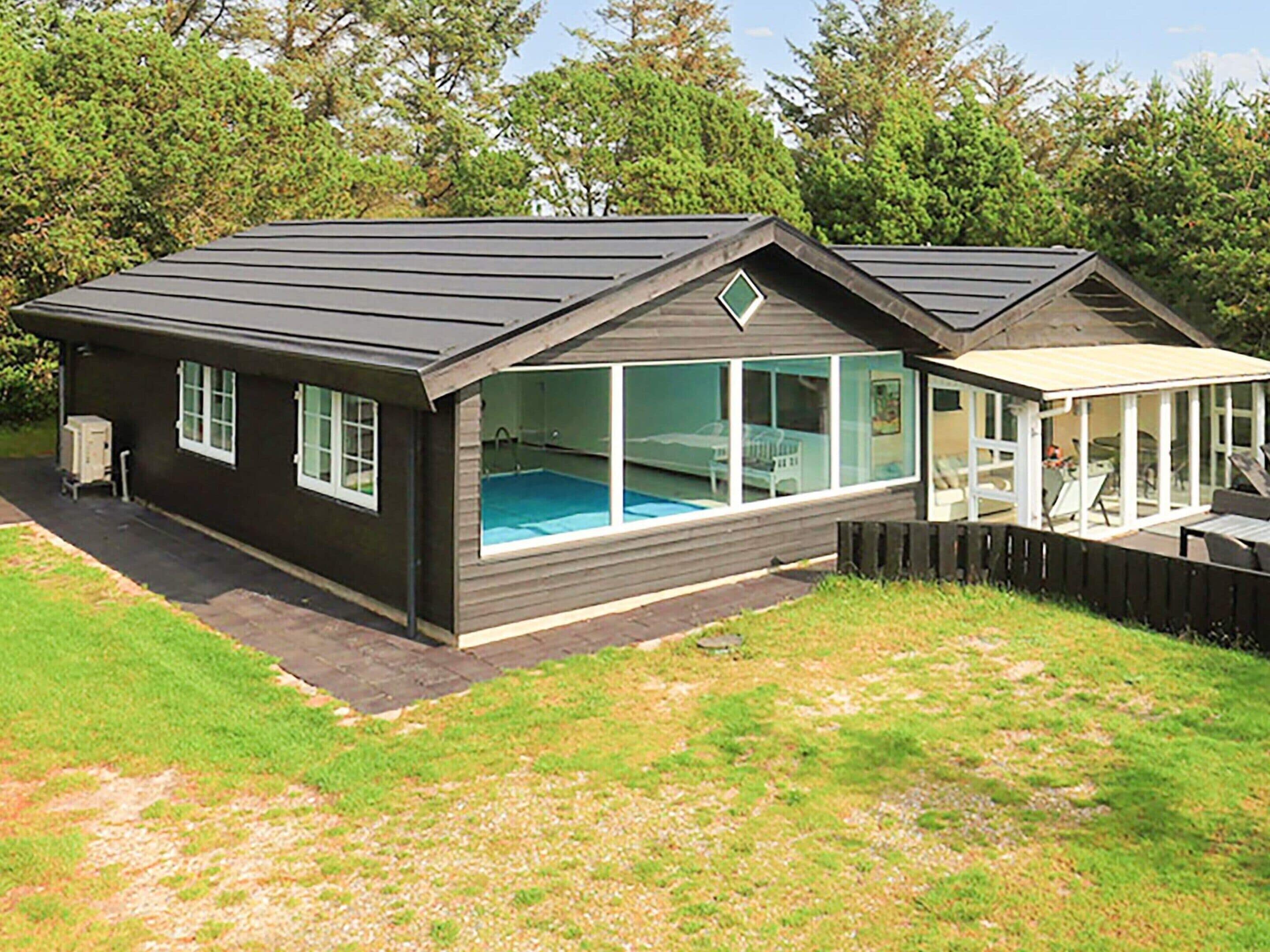 A modern house with a swimming pool, large windows, and a covered patio area.