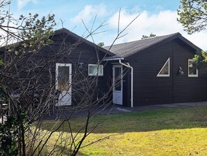 A modern two-story house with a dark exterior, a visible garage door, and a small front yard. - 4 Star Holiday Home in Vejers Strand (Vejers Strand)