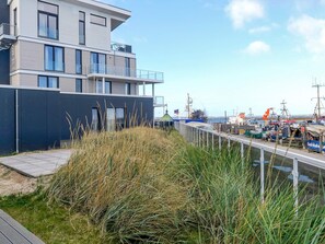 Un edifici modern amb diversos pisos i balcons que donen a una marina plena de vaixells.
