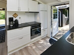 A compact kitchen with white cabinets, a black countertop, and a stainless steel sink. - 5 Person Holiday Home in Oksbol-by Traum (Oksbol)