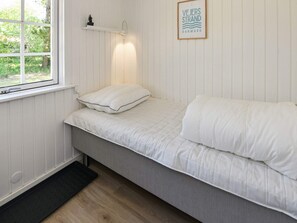 A single-bed room with a window, a wall-mounted shelf with a plant, and a framed sign. - 5 Person Holiday Home in Oksbol-by Traum (Oksbol)
