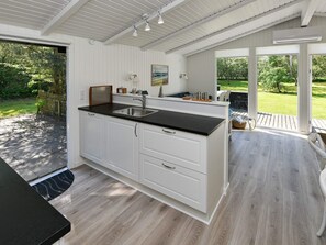 A modern kitchen with a black countertop, white cabinetry, and a large window offering a view of the outdoors. - 5 Person Holiday Home in Oksbol-by Traum (Oksbol)