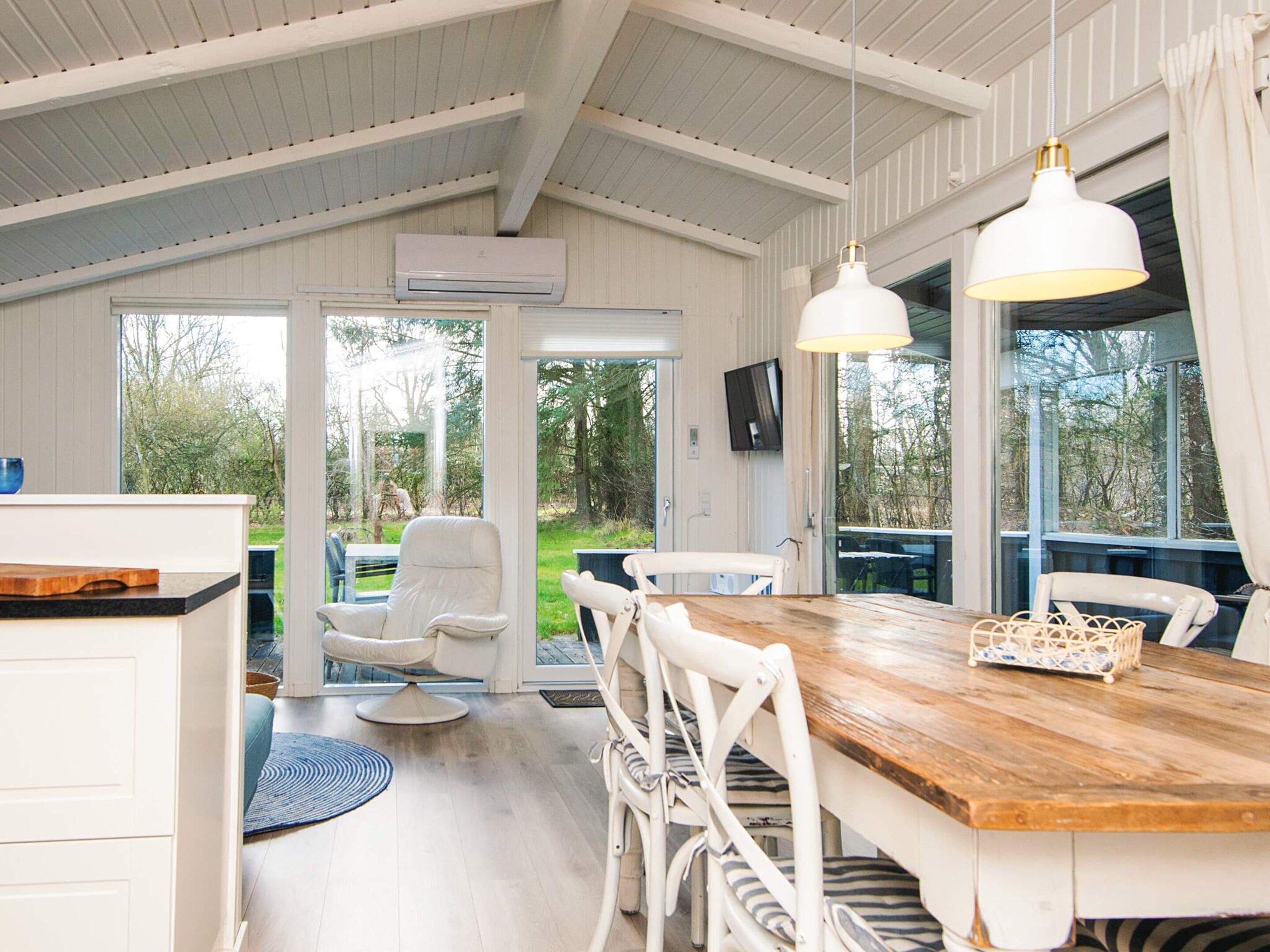 A spacious dining area with a wooden table, white chairs, and pendant lighting.