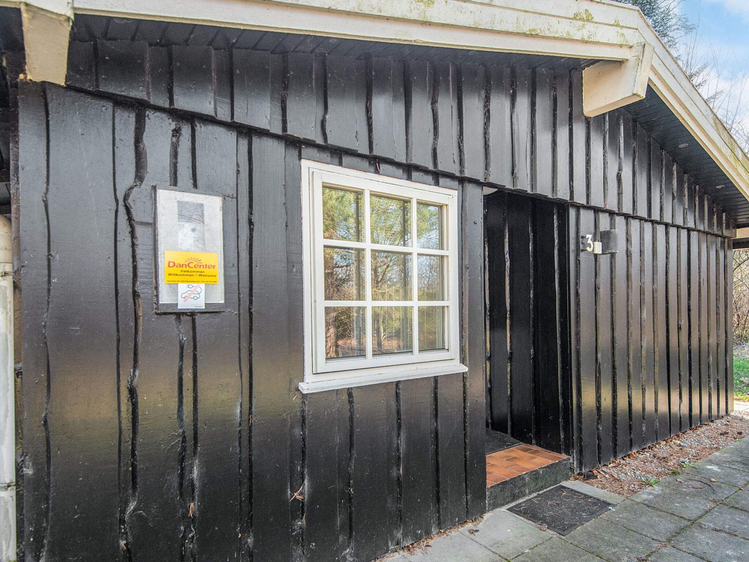 A building with a black exterior, a white-framed window, and a door.
