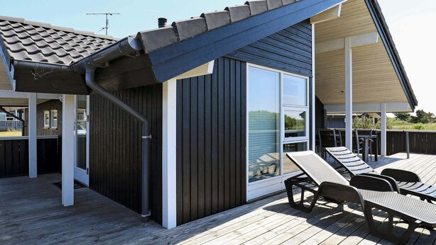 Een houten terras met een overdekte zithoek en een schuifpui.