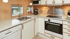 Een keuken met witte kasten, roestvrijstalen apparatuur en houten wanden.