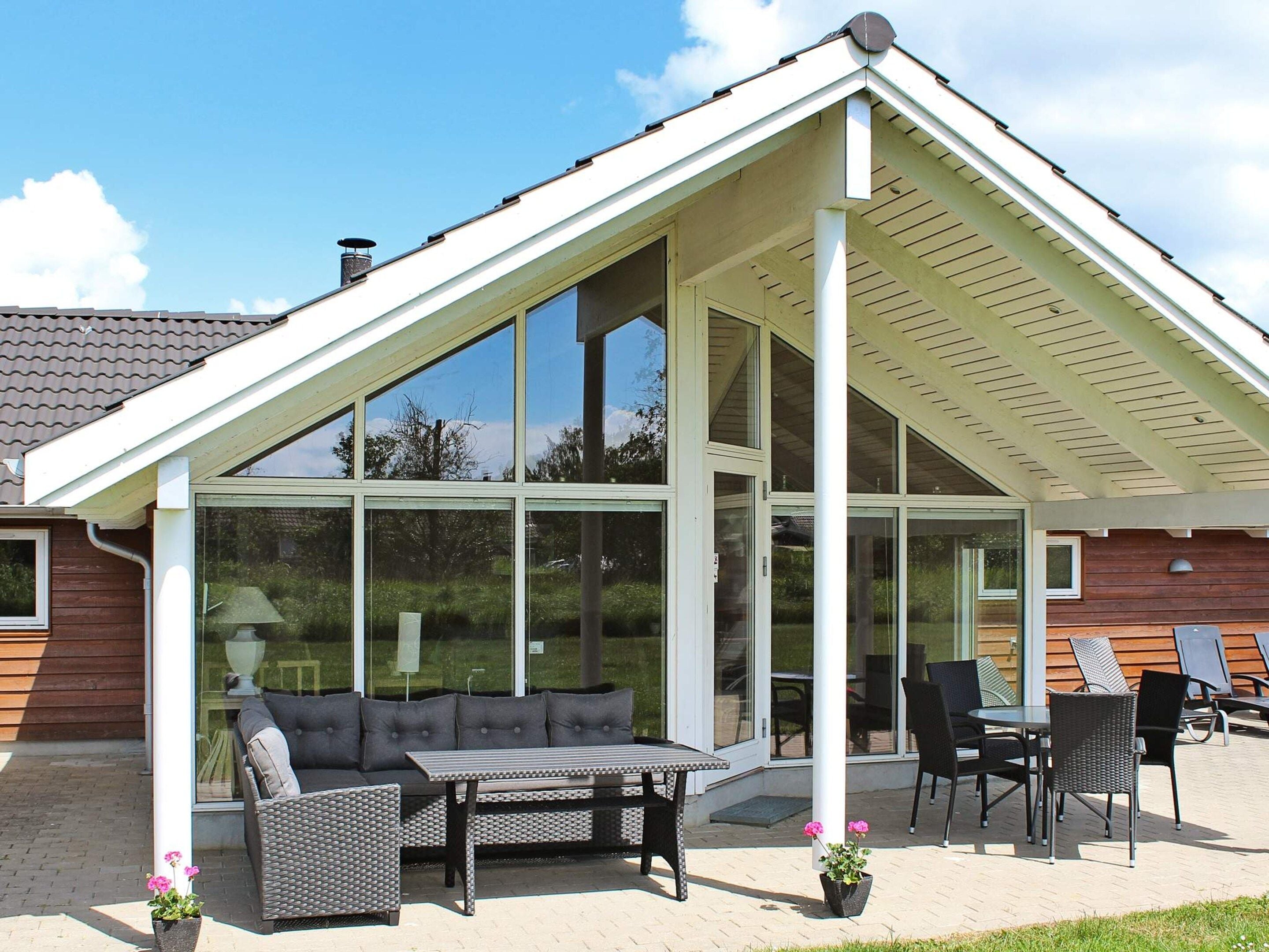 A covered patio area with a seating arrangement, a table, and chairs.