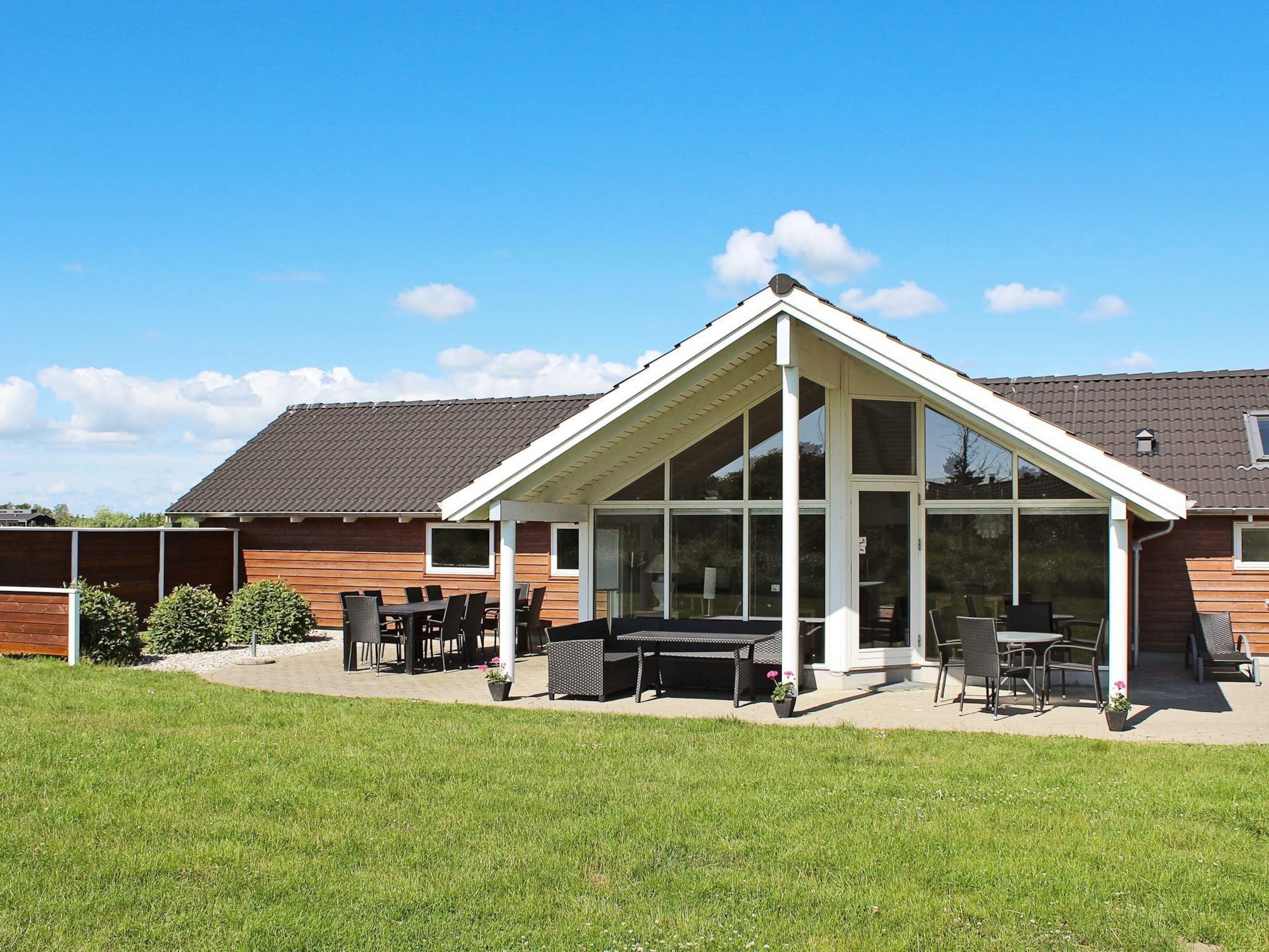A house with a covered patio area, a dining set, and a lawn.