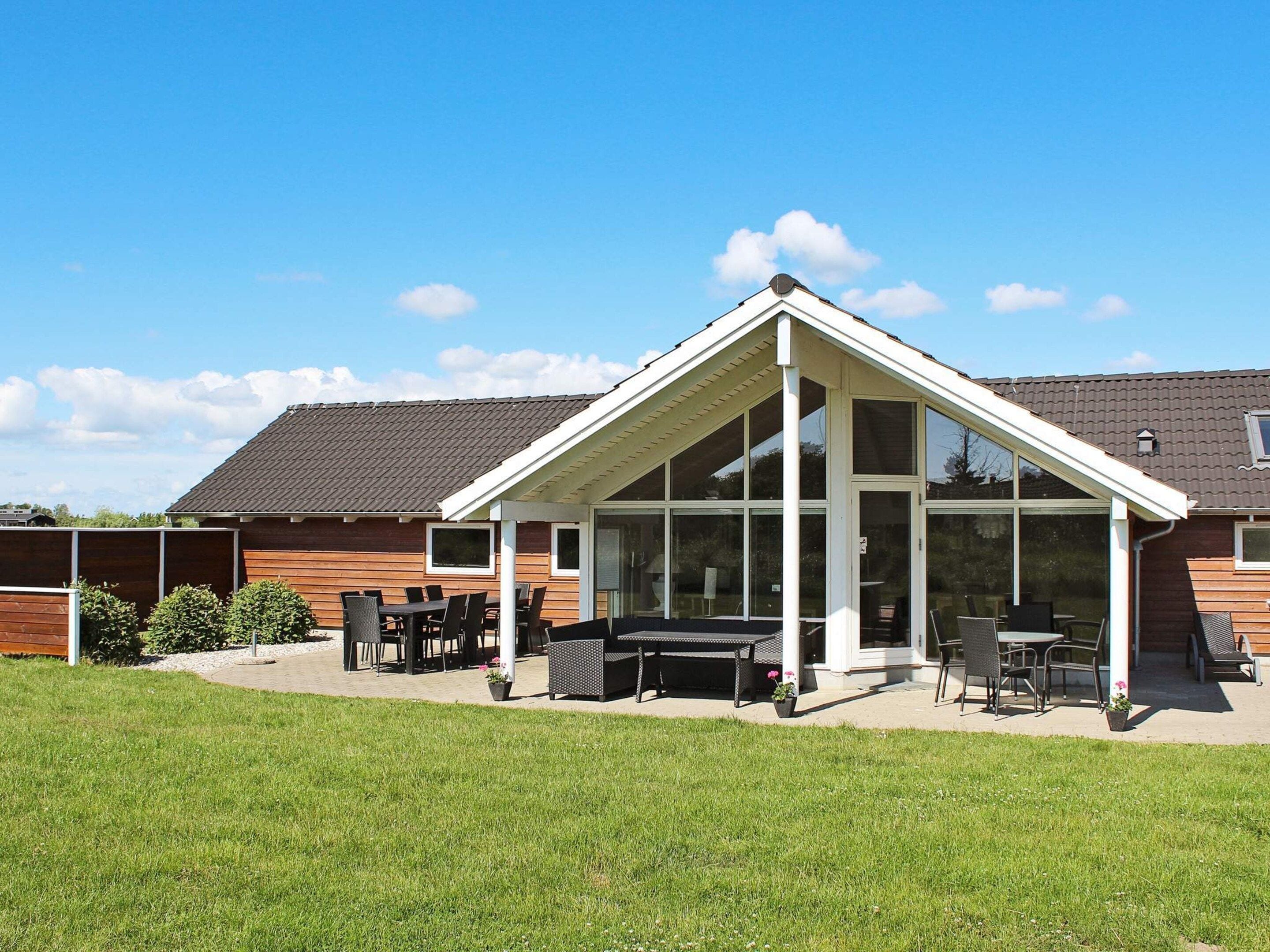 Een huis met een overdekte patio, een eettafelset en een gazon.
