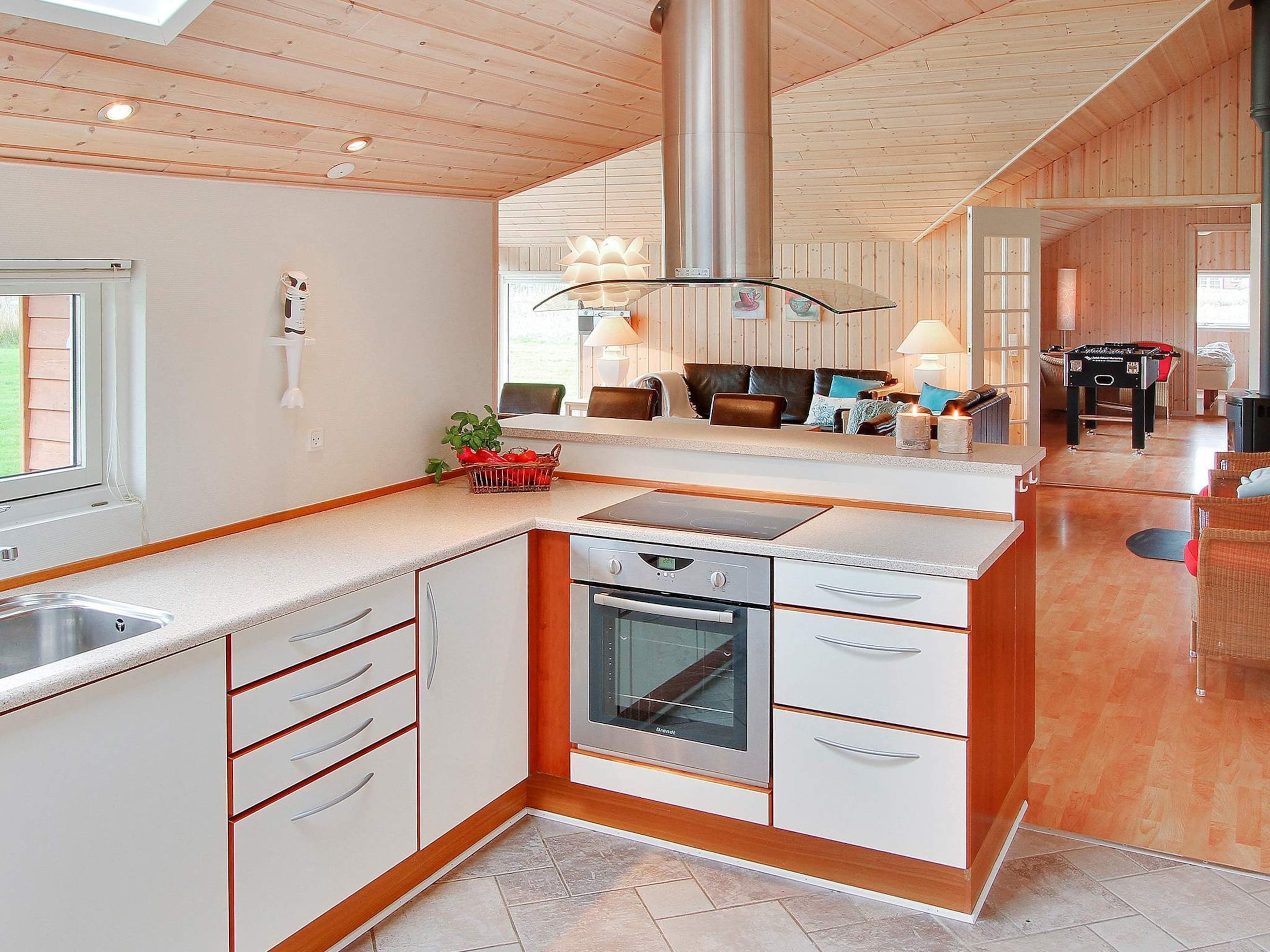 A modern kitchen with a built-in oven and a dining area with a sofa and table.