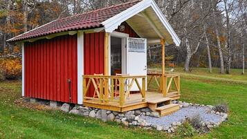 A small red and white building with a wooden deck and a stone foundation.