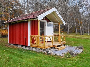 A small red and white building with a wooden deck and a stone foundation. - 6 Person Holiday Home in Askeron (Hjaelteby)