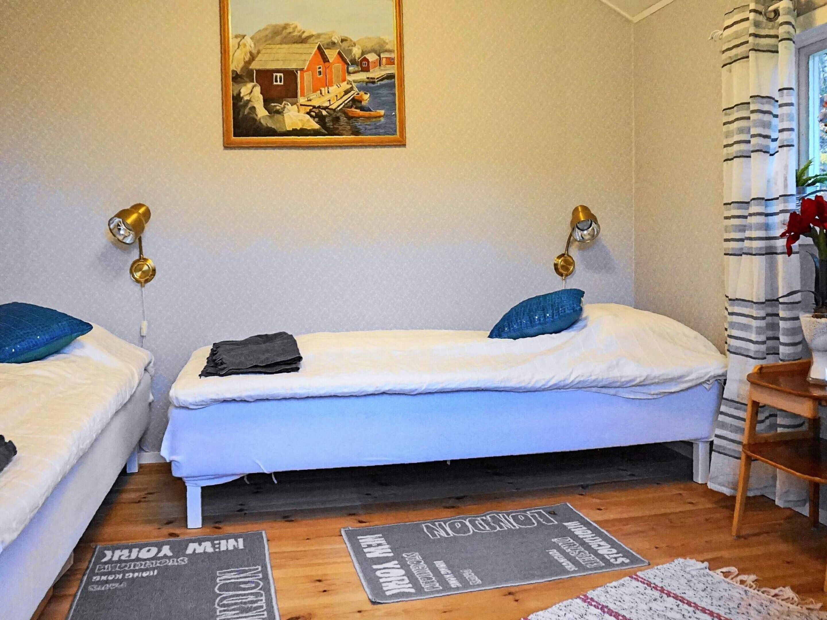 A room with two beds, a painting on the wall, and a window with curtains.