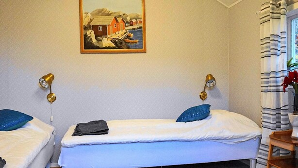 A room with two beds, a painting on the wall, and a window with curtains. - 6 Person Holiday Home in Askeron (Hjaelteby)