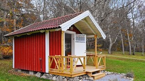 A small red and white building with a wooden deck and a stone foundation. - 6 Person Holiday Home in Askeron (Hjaelteby)